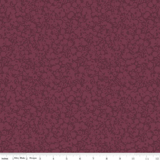 A close-up of a repeating floral pattern in deep burgundy and muted mauve, with a ruler strip along the bottom showing scale.
