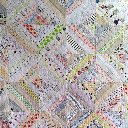 Quilt with a geometric pattern featuring various colors and textures.