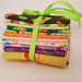 Stack of colorful fabric squares tied with a green ribbon on a white background