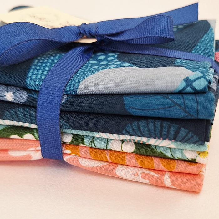Stack of colorful fabric bundles tied with a blue ribbon on a light background