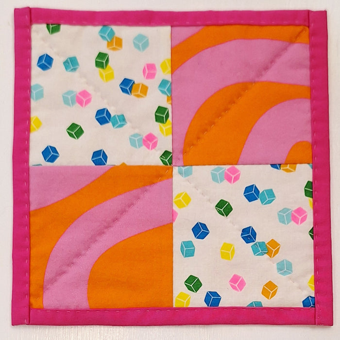Colorful quilt block with geometric patterns on a white background
