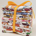 Stack of colorful fabric rolls tied with a yellow ribbon on a light background