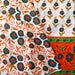 Decorative fabric with floral patterns in orange, green, and black on a white background.