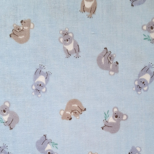 Light blue fabric with a repeating pattern of cute cartoon koalas in muted gray, brown, and white tones.