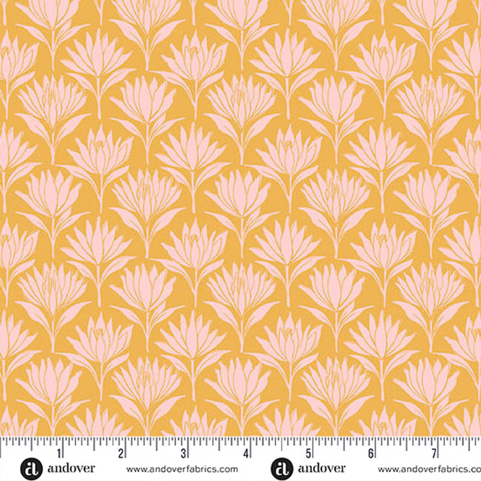 A repeating floral pattern fabric swatch with pale pink stylized flower motifs on a warm mustard yellow background, shown with a ruler along the bottom edge for scale. Andover branding is visible at the bottom.