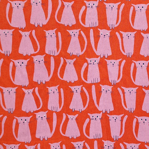 close up of fabric with hand drawn pink cats on a red background.