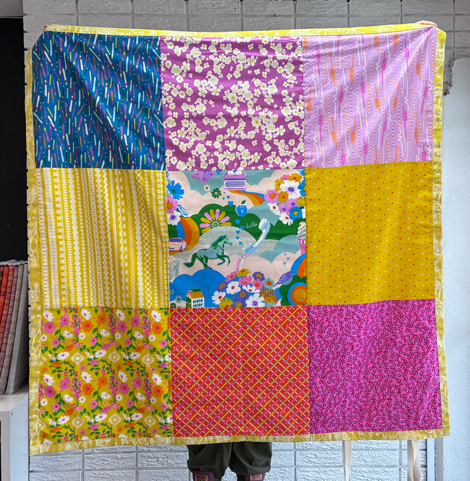 Colorful patchwork quilt with various patterns draped over a person.