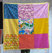 Colorful patchwork quilt with various patterns draped over a person.