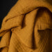 Close-up of a textured mustard yellow fabric with a dark background