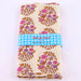 Folded fabric with floral pattern and 'Petit Pan' label on a white background