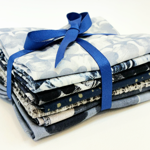 Stack of fabric bundles tied with a blue ribbon on a white background
