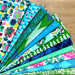 Stack of colorful fabric swatches with various patterns on a wooden surface