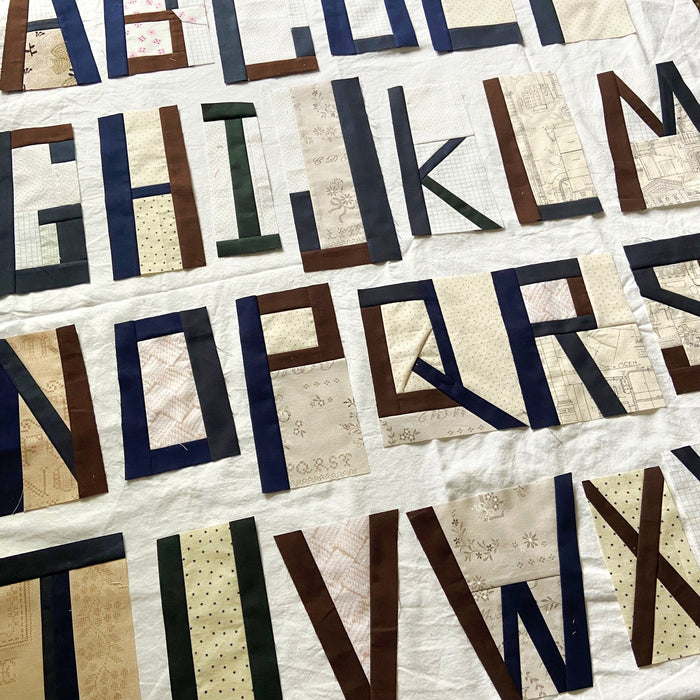 Quilt with fabric letters spelling out the alphabet on a white background