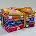 A stack of colorful patterned fabric squares tied together with a yellow ribbon, photographed on a plain light background.