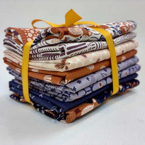 A stack of folded patterned fabric pieces tied together with a bright yellow ribbon, photographed on a clean white studio background.