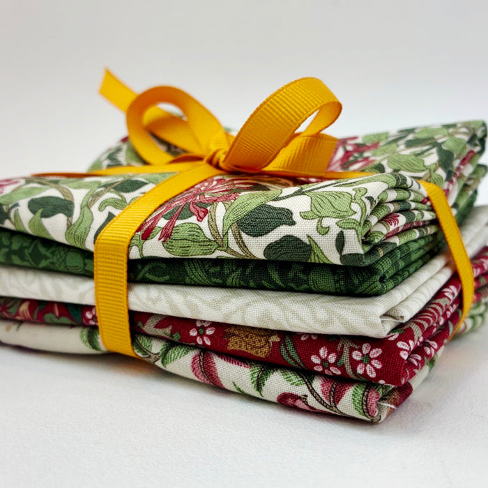 A stack of folded patterned fabric pieces tied with a bright yellow ribbon, photographed on a clean white background.