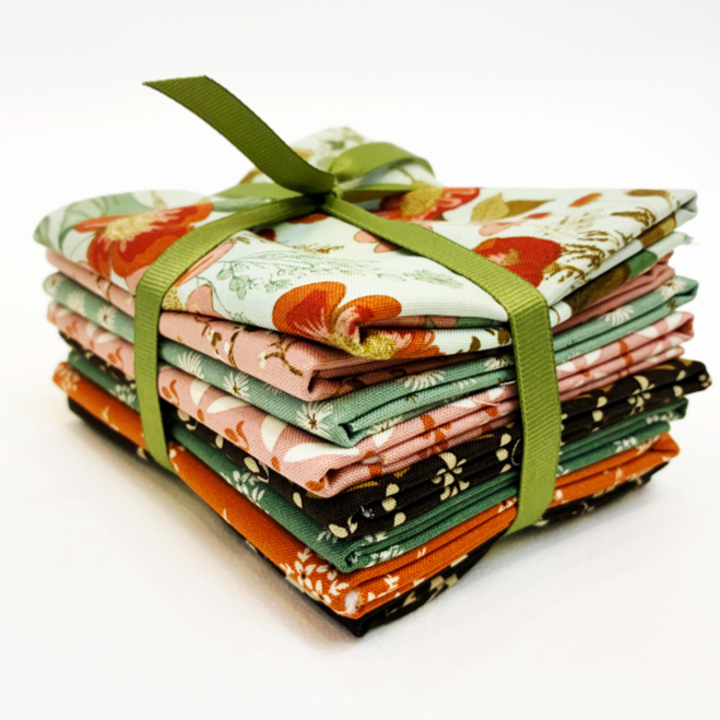 Stack of fabric bundles tied with a green ribbon on a white background
