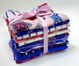 Stack of colorful fabric bundles tied with a pink ribbon on a white background