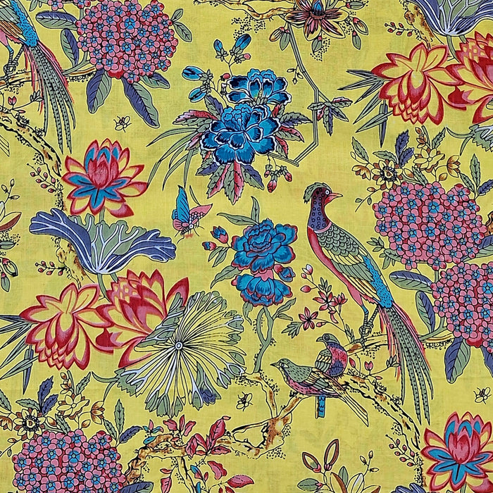 A close-up of a fabric  pattern featuring a classic Indian-style floral and bird design on a bright yellow background. The print includes blue lotus flowers, pink hydrangeas, blue birds, and green foliage.