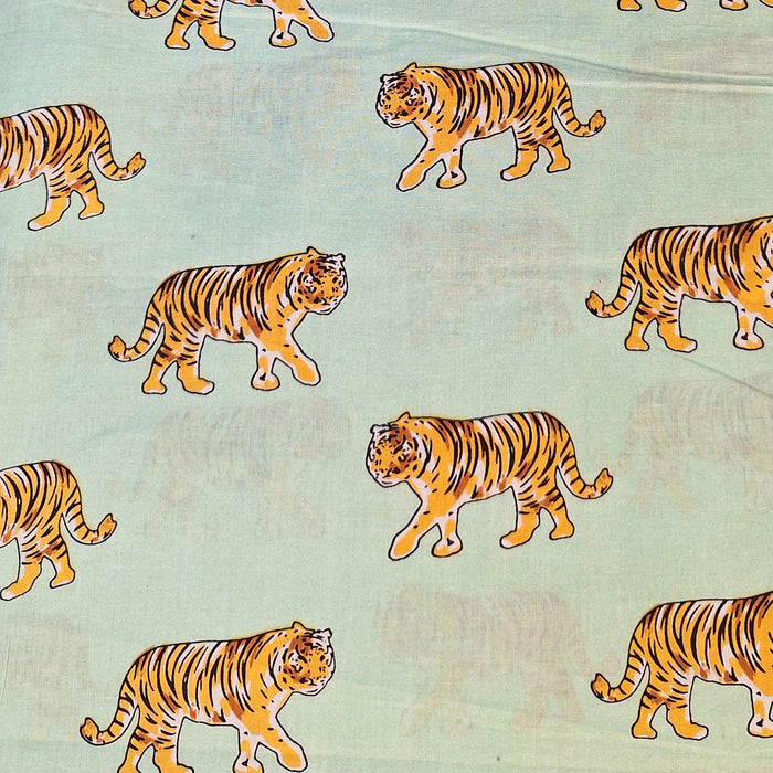 close up of fabric design featuring yellow tigers on pale green background