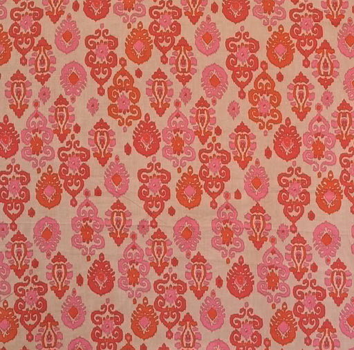 A close-up of a woven fabric with an all-over repeating damask pattern in shades of pink, coral, and orange on a warm beige background.