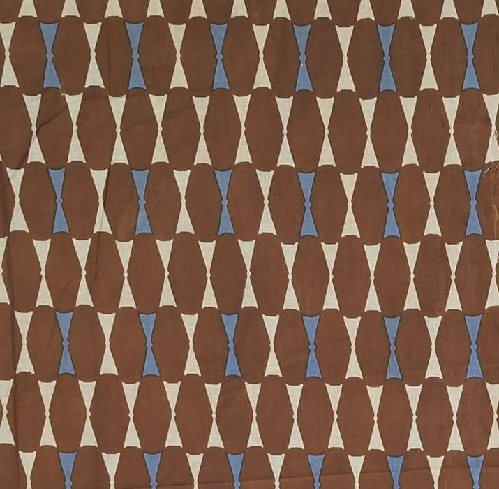 A close-up of a patterned fabric or wallpaper featuring a repeating geometric design of brown elongated ovals, cream triangles, and small light blue diamond accents.