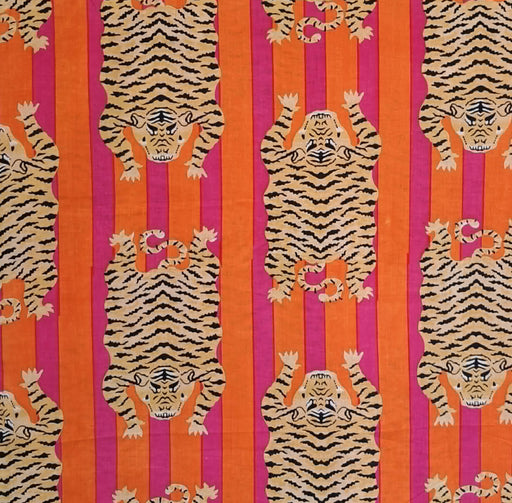 A close-up of a patterned fabric featuring repeated tiger illustrations in beige and black over vertical stripes of orange and bright pink.