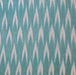 A close-up of a fabric pattern featuring a repeating vertical ikat-style design in teal blue and off-white.
