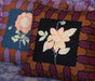 Two embroidered pillows with floral designs on a patterned fabric background.