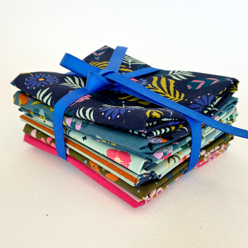 Stack of colorful fabric bundles tied with a blue ribbon on a white background
