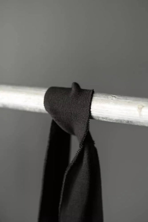 Black fabric draped over a metal rod against a gray background
