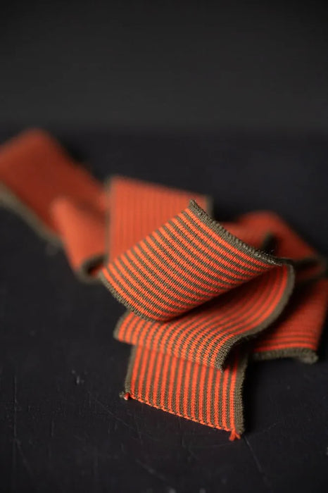 Close-up of orange ribbon with striped pattern on a dark background