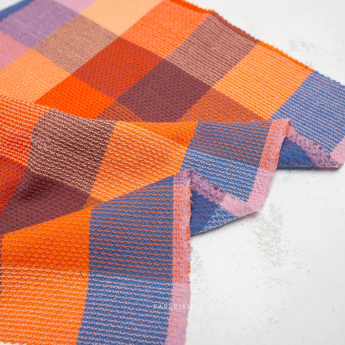 close up of waffle weave fabric in bright orange, blue and pale pink
