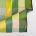 Close up of waffle weave fabric in shades of green and yellow checks
