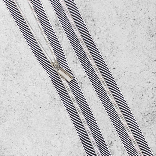Two parallel black and white striped zippers on a textured gray background