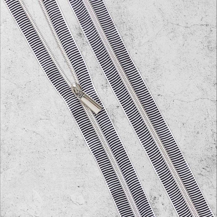Two parallel black and white striped zippers on a textured gray background