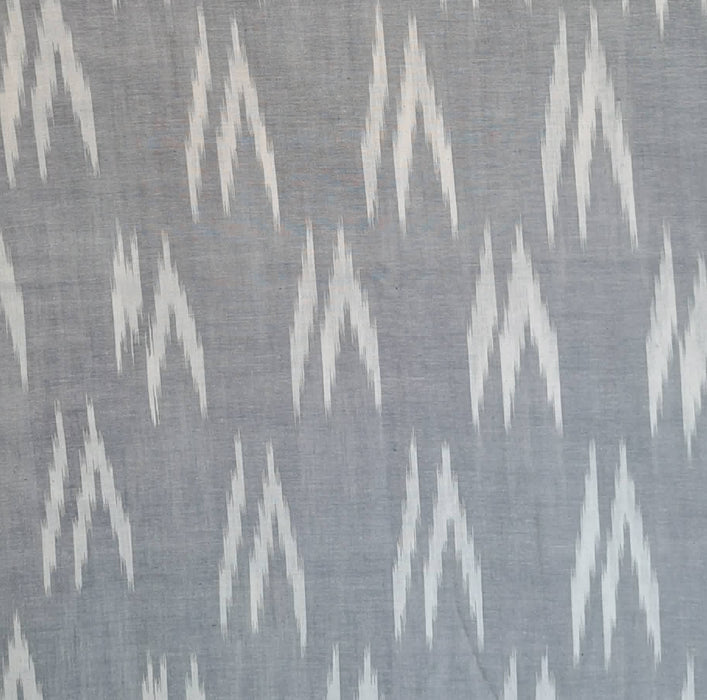 A close-up of a woven fabric with a repeating white ikat chevron pattern on a muted gray background.