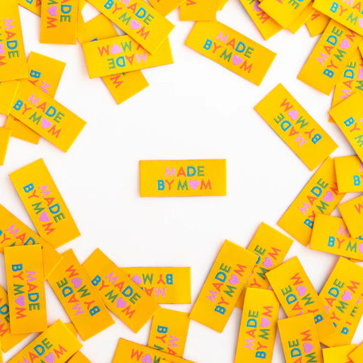 Scattered yellow labels with 'Made by Mom' text on a white background