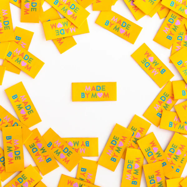 Scattered yellow labels with 'Made by Mom' text on a white background